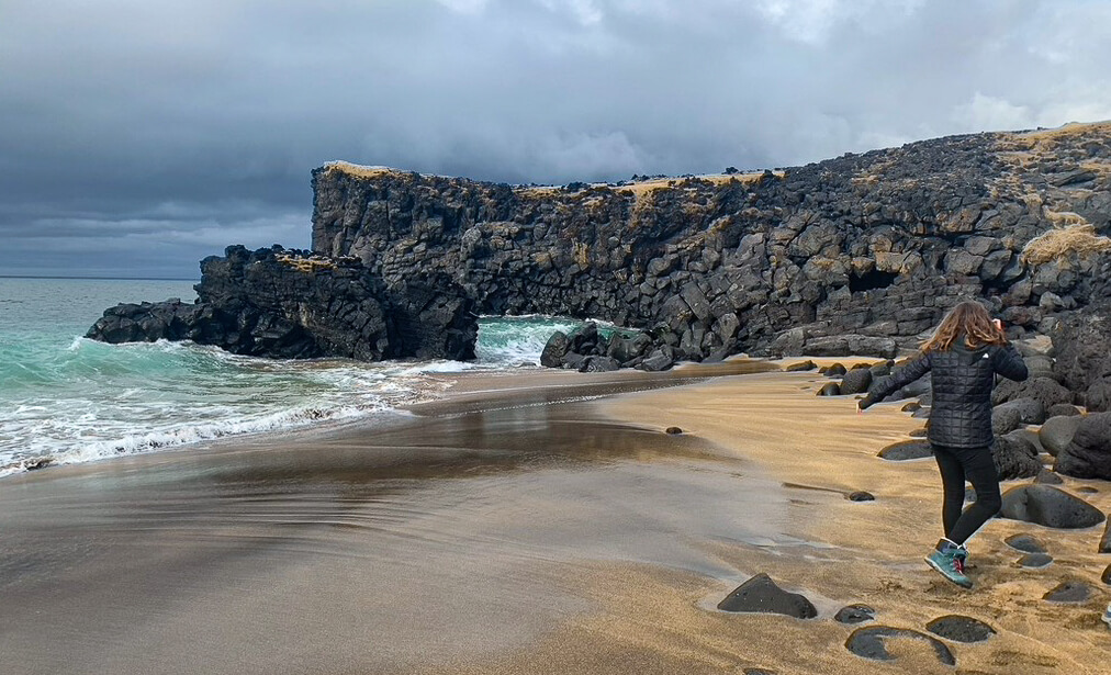 Girl jumping on rocks on a beach on the Snaefellsness Peninsula in Iceland