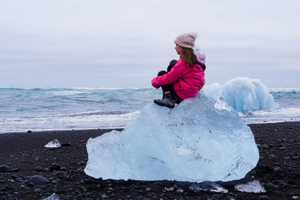 Girl sitting on iceberg on the Iceland South Coast